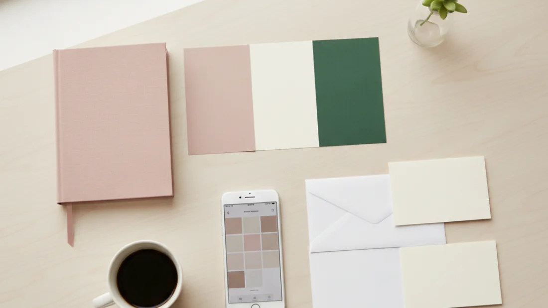 A new business brand kit on a desk: color swatches, notebook, cards and a palette on a phone